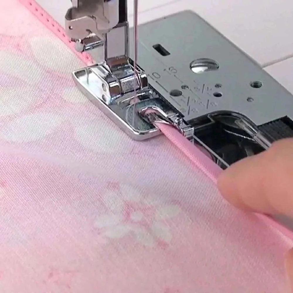 Máquina de coser Singer con tela rosa y prensatelas metálico en acción cosiendo borde rosa.