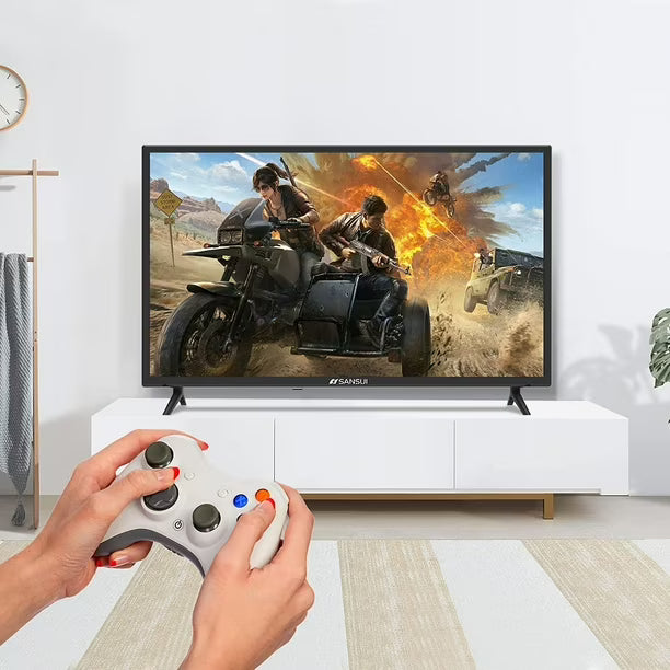 Televisor Sansui 32" HD con imagen de videojuego y manos sosteniendo control gris y blanco.