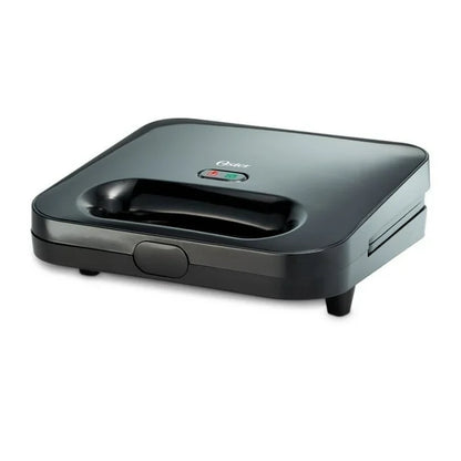 Sandwichera compacta Oster negra con mango integrado y luces indicadoras de encendido y listo.