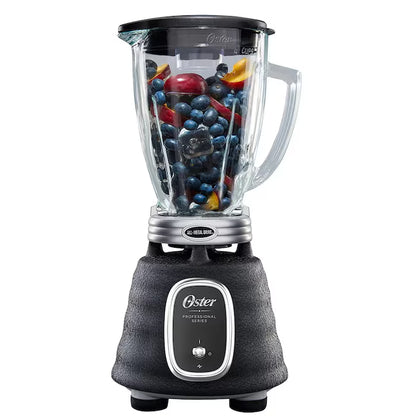 Licuadora Oster negra con base texturizada, vaso de vidrio transparente lleno de frutas frescas.