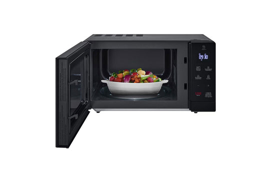 Microondas LG negro 1.1 pies con puerta abierta y plato blanco con ensalada adentro, pantalla digital y control touch.