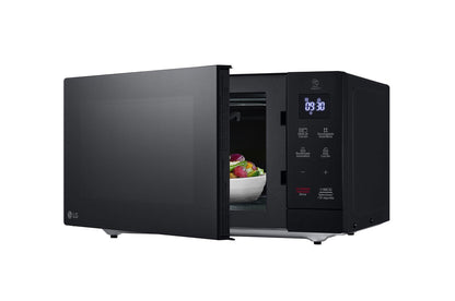 Horno microondas LG negro 1.1 pies con panel táctil digital y puerta abierta mostrando interior con plato y fruta.