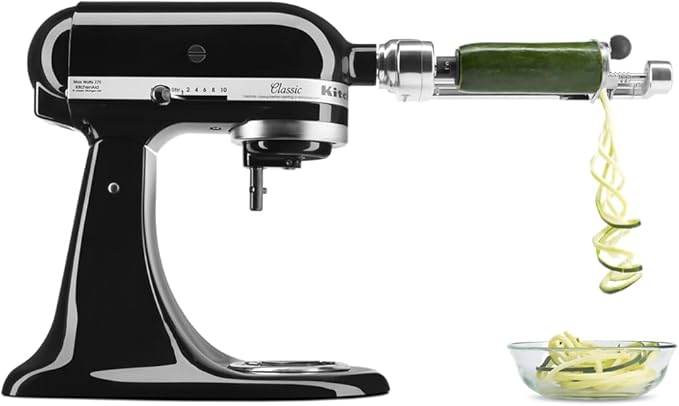 Batidora de pie KitchenAid negra con brazo extensible y espiral de pepino en accesorio triturador.