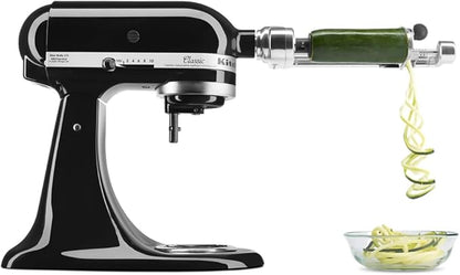 Batidora de pie KitchenAid negra con brazo extensible y espiral de pepino en accesorio triturador.