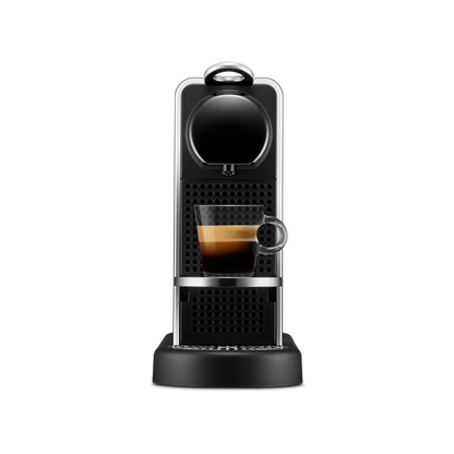 Cafetera Nespresso Citiz color plata con bandeja de goteo y espresso servido en vaso transparente.