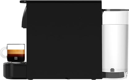 Cafetera Nespresso Essenza Mini negra con depósito de agua transparente y taza con espresso crema espesa.