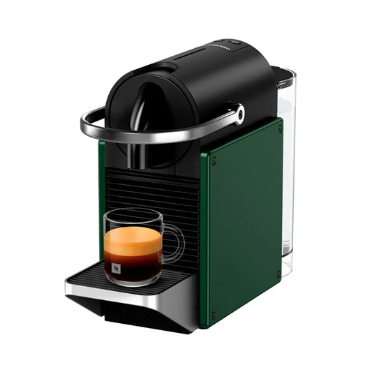 Cafetera Nespresso Pixie compacta verde con soporte metálico y vaso de espresso con crema visible.