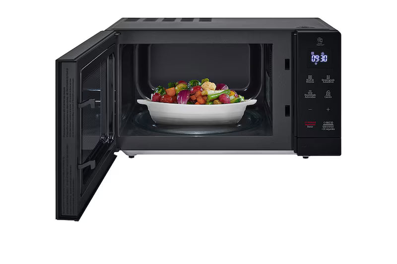 Microondas LG negro 1.1 pies con puerta abierta y plato con ensalada adentro.