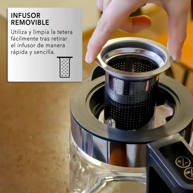 Mano quitando infusor negro perforado de tetera digital RCA con jarra de vidrio transparente y base negra.